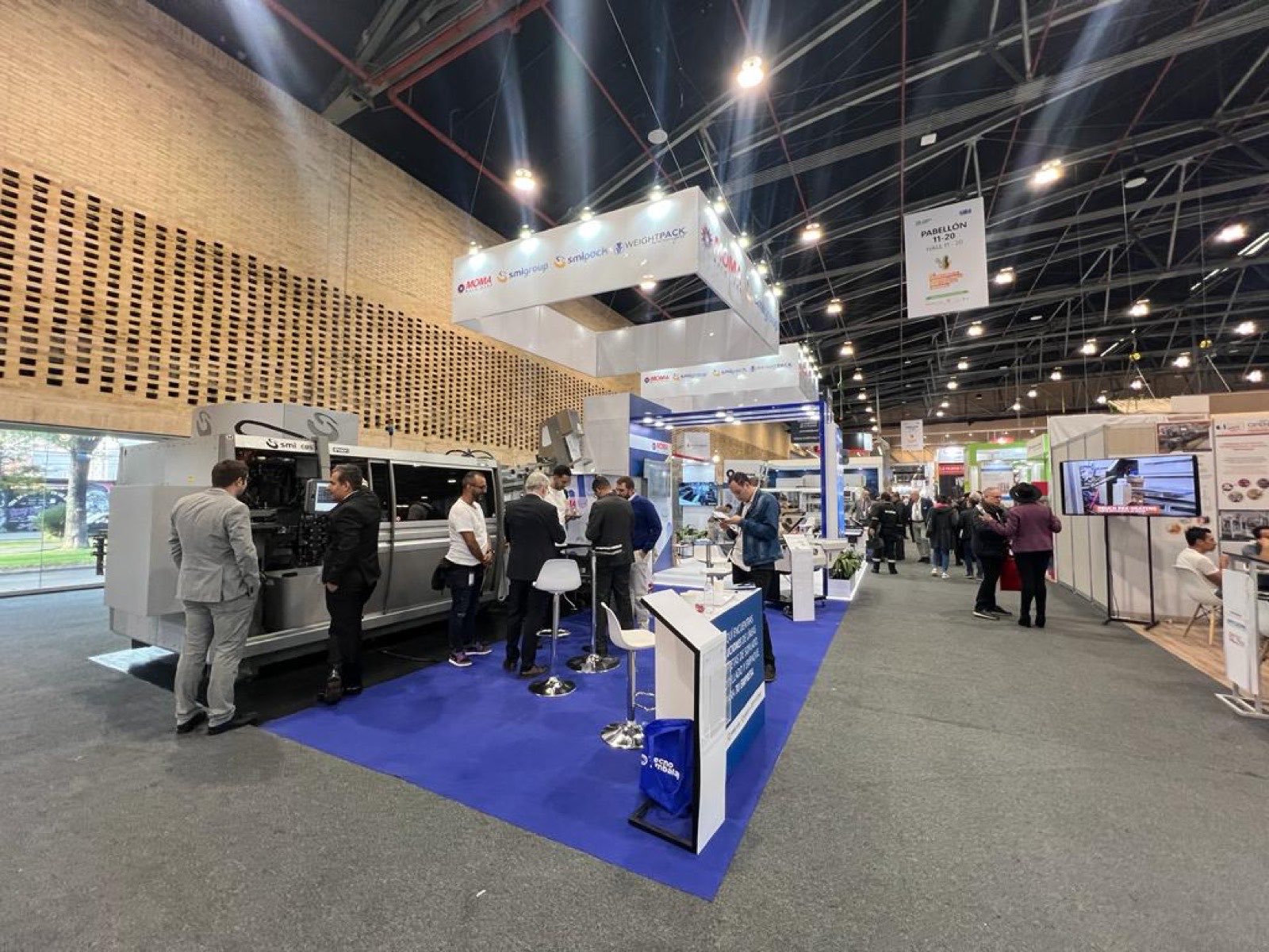 Stand de MOMA Machinery y SMI Group con una sopladora en exhibición